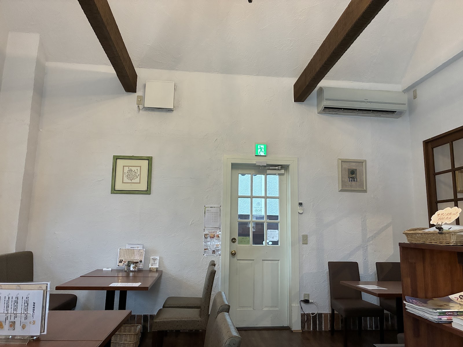 白壁と木の梁のカフェの店内。奥に木のドア