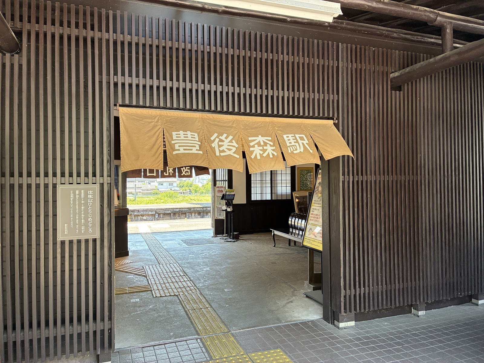 豊後森駅の入口。木の格子と黄色い暖簾