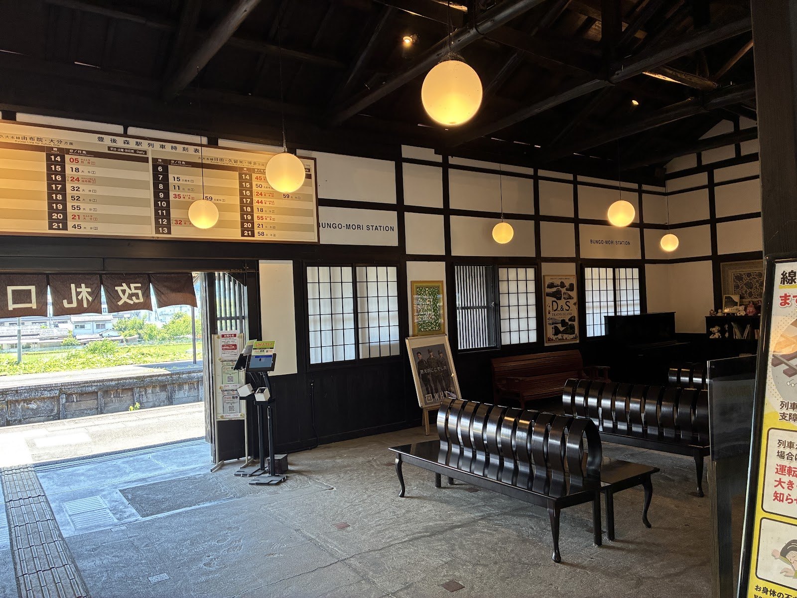 木造の待合室。丸い照明と、奥に置かれたピアノ