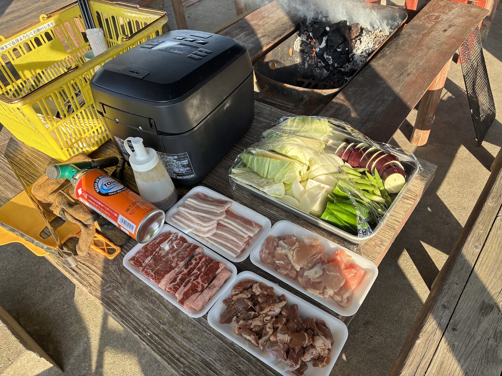バーベキューの食材。肉のパックと野菜がテーブルに並んでいる