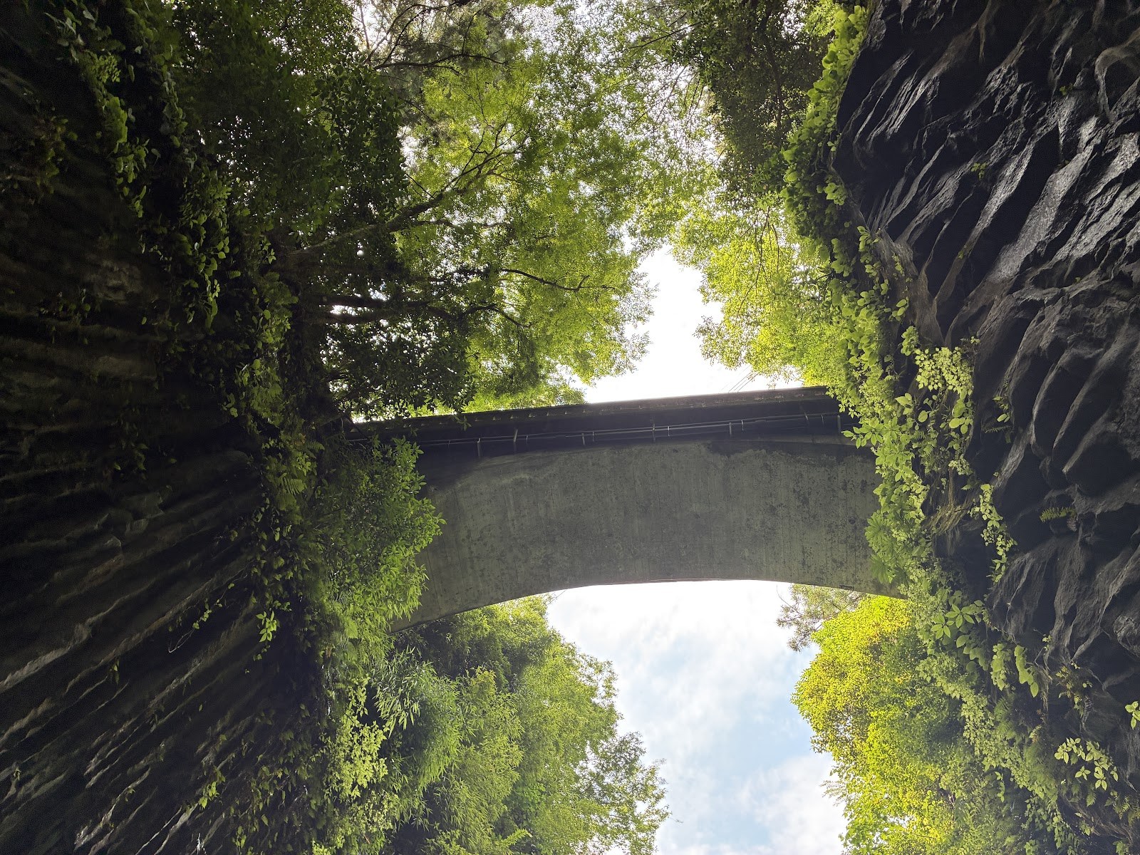 峡谷を渡るアーチ橋を舟の上から見上げた写真