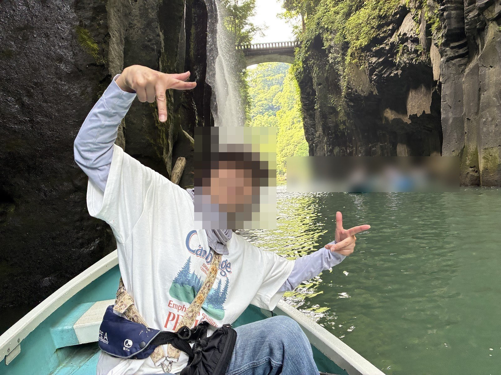 貸しボートの上でポーズをとる女性と、背景の真名井の滝と橋