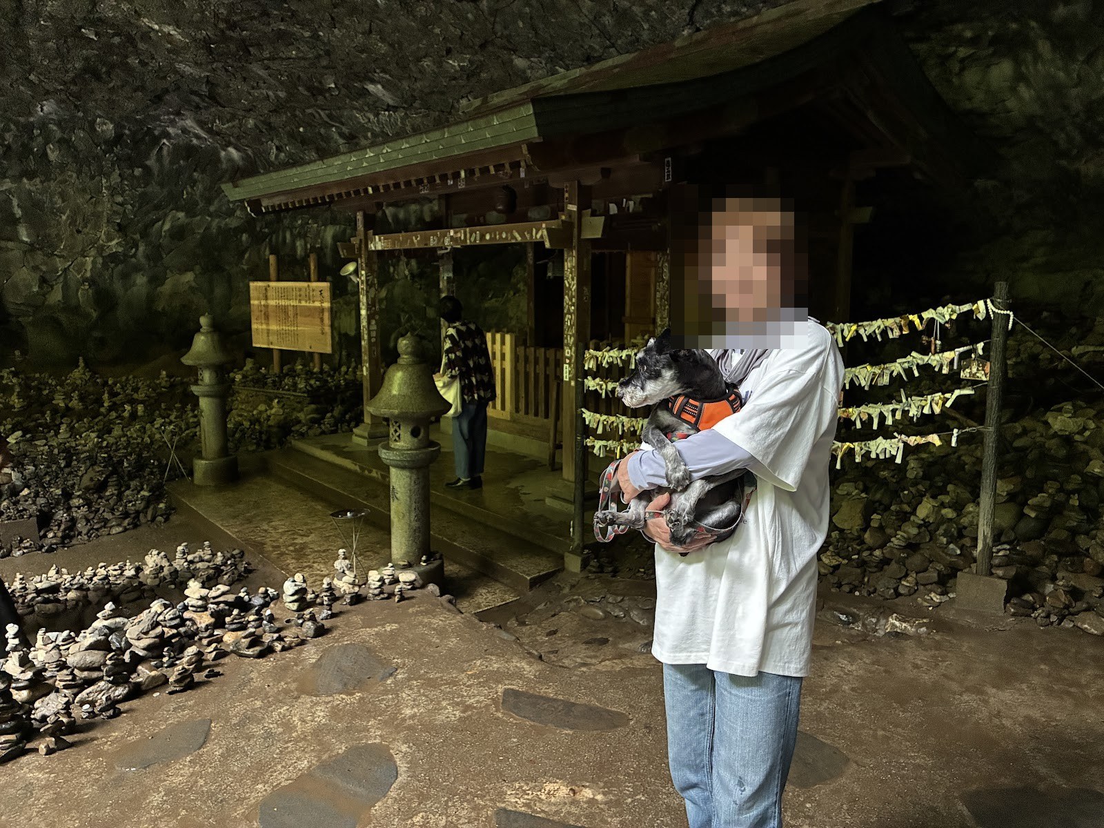 天安河原の洞窟の前で犬を抱いて立つ人