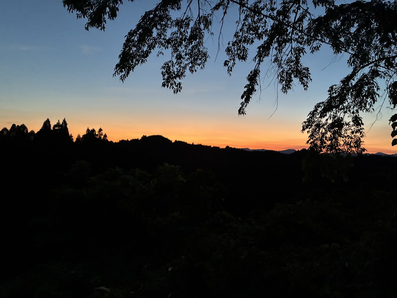 山の稜線に沈む夕日とオレンジ色の空
