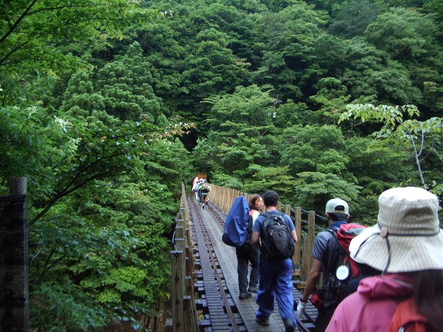 鉄橋の上を一列で歩く登山者たち