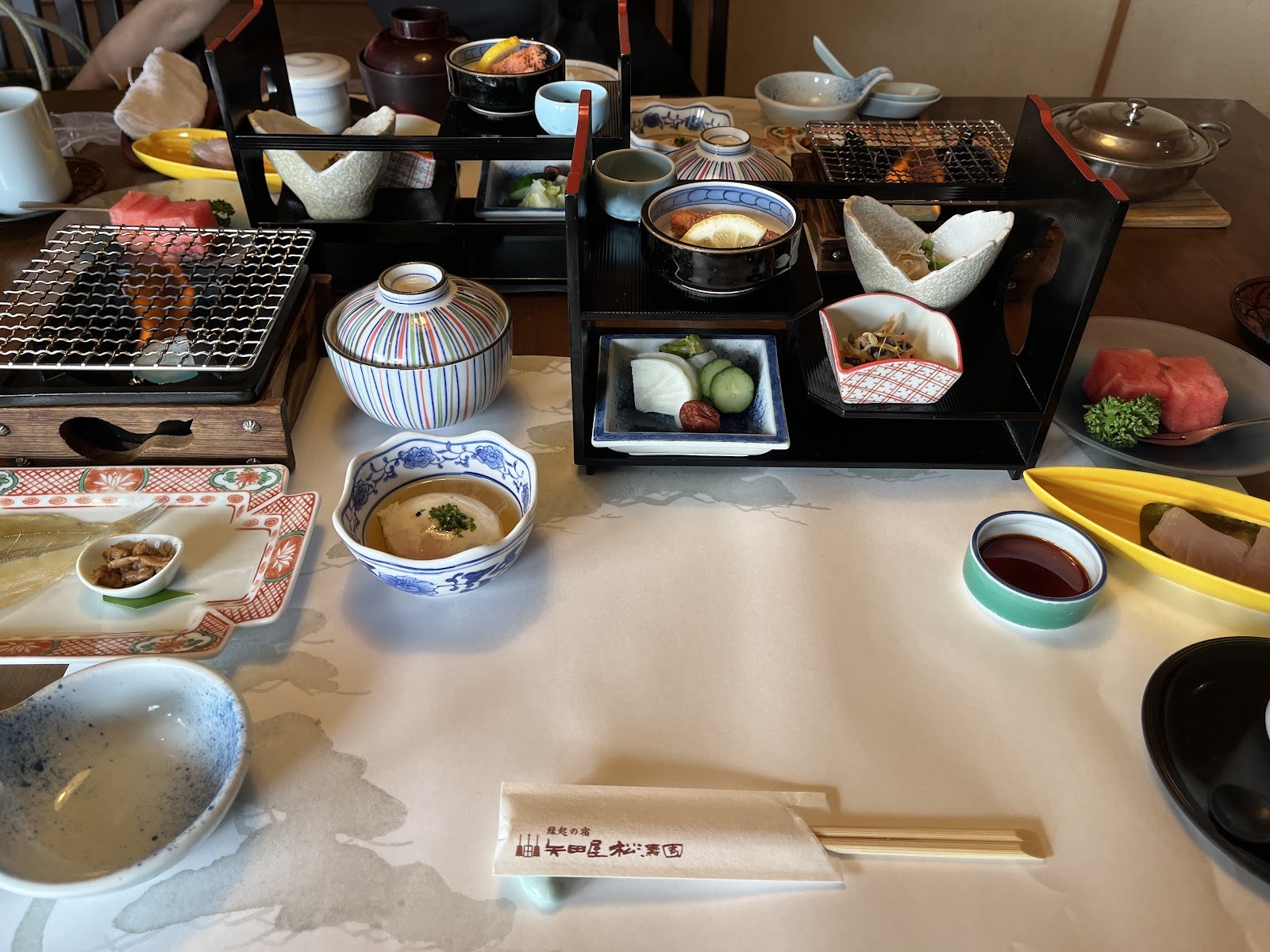 朝食の膳。焼き魚、小鉢、釜、味噌汁が並ぶ