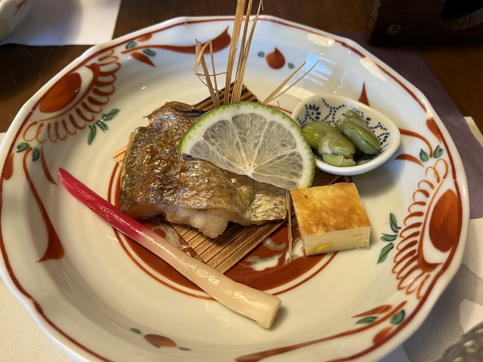 赤絵の皿に盛られた焼き魚と、あしらいの野菜