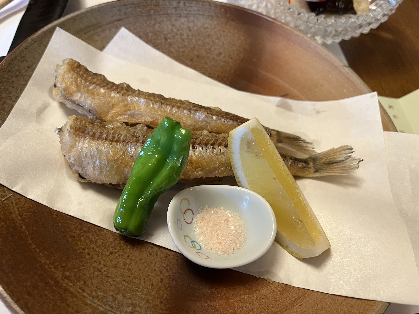 杉板に載った焼き魚と、ししとう、塩