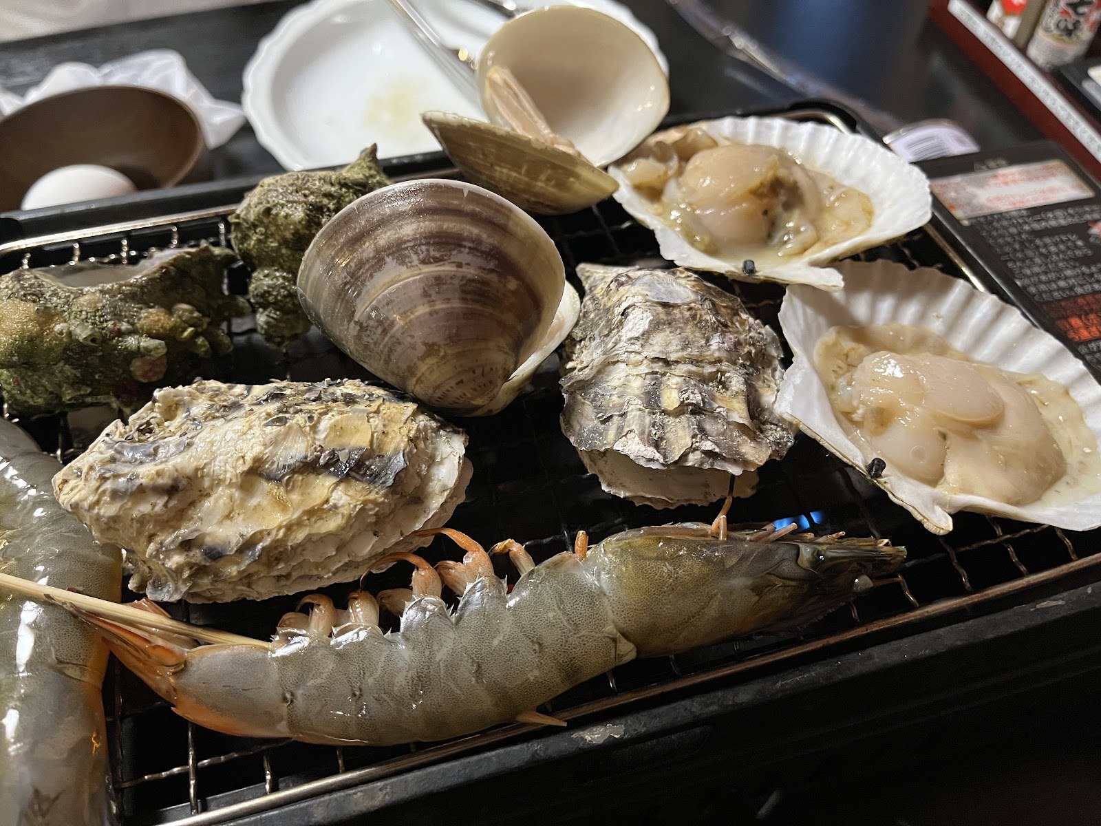 網の上で焼かれる牡蠣・ホタテ・えびの浜焼き