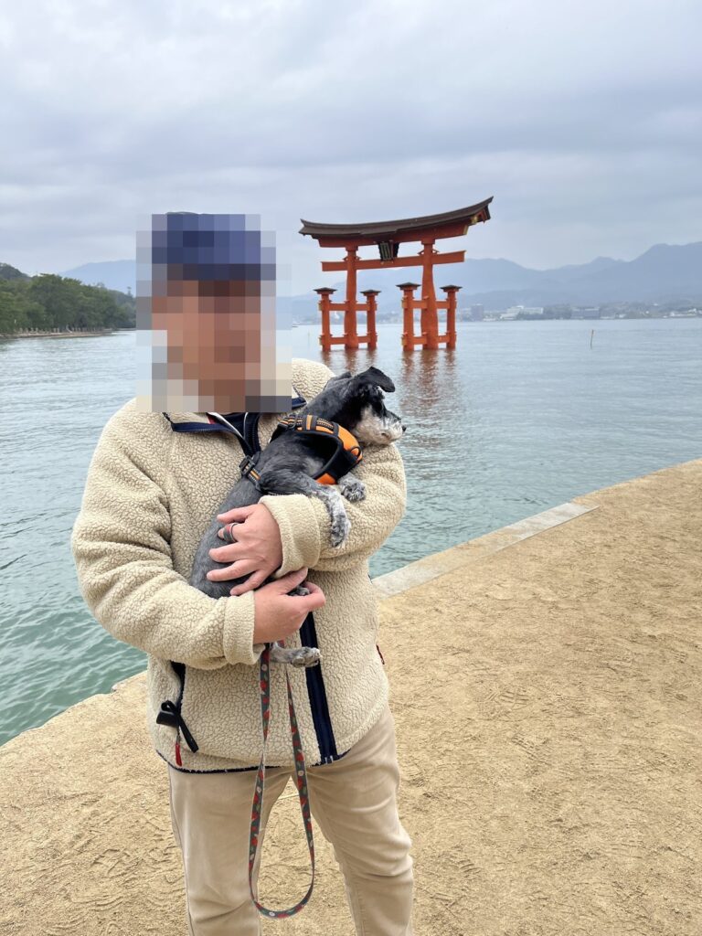 満潮の大鳥居を背に犬を抱いて立つ人