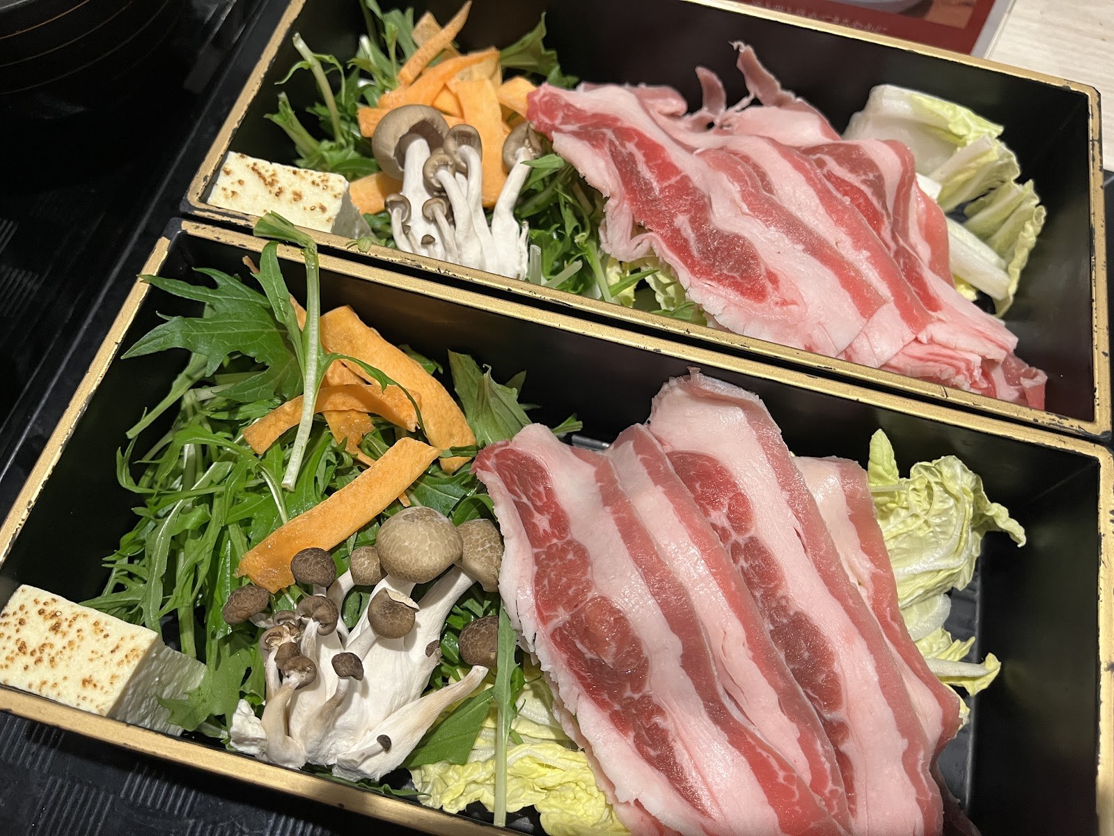 重箱に盛られたすき焼きの具材。牛肉と野菜