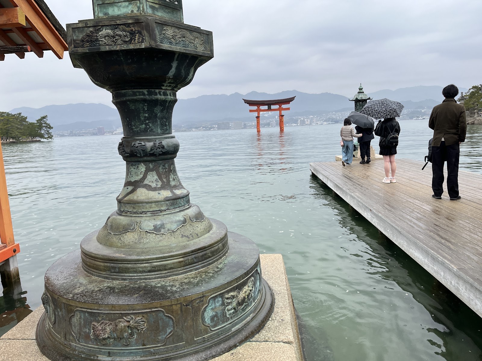 青銅の灯籠ごしに見る雨の日の大鳥居