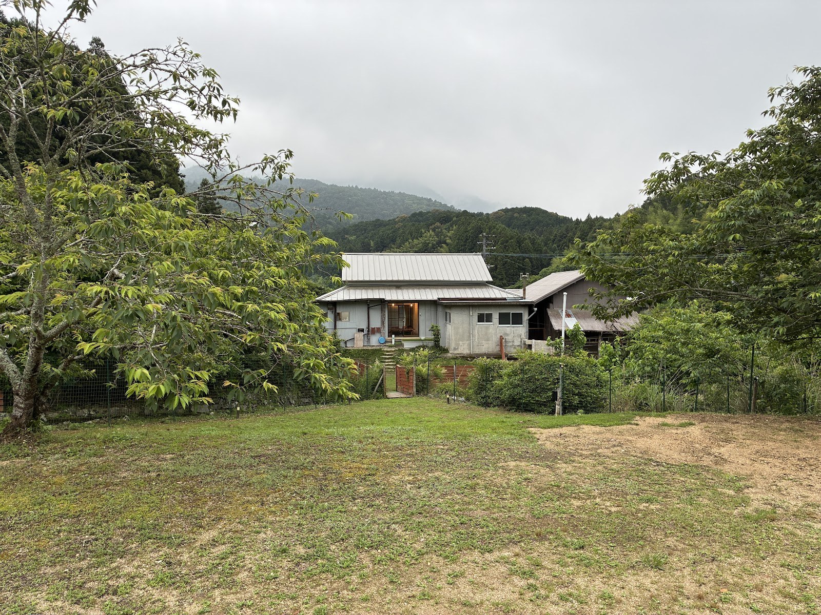 山あいの一軒家。手前に芝生が広がる