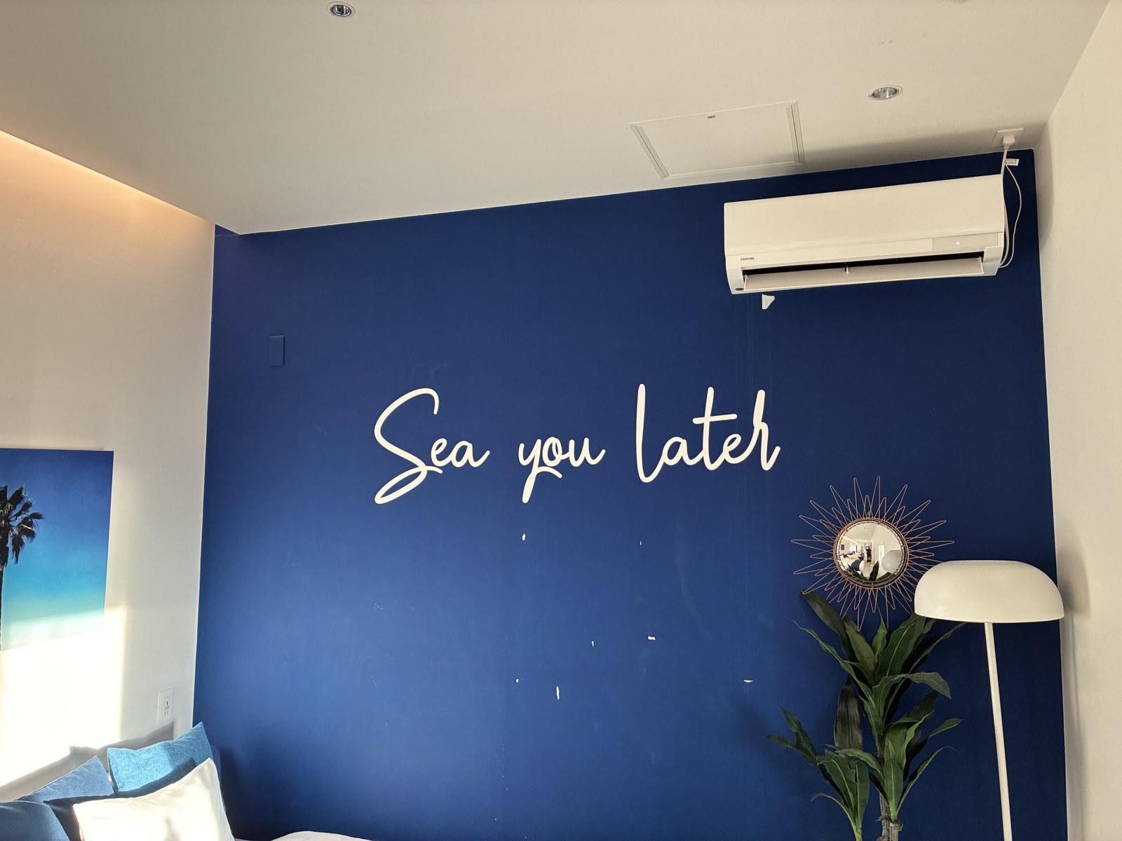 客室の紺のアクセントウォールに光る「Sea you later」のネオンサイン