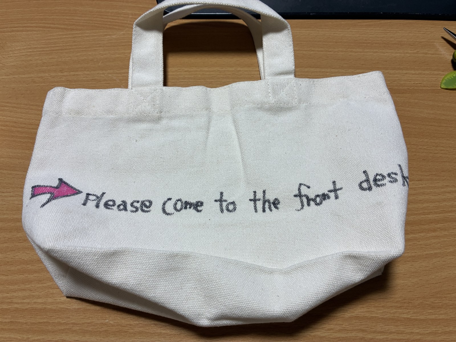 同じトートバッグの裏。「Please come to the front desk」の刺繍