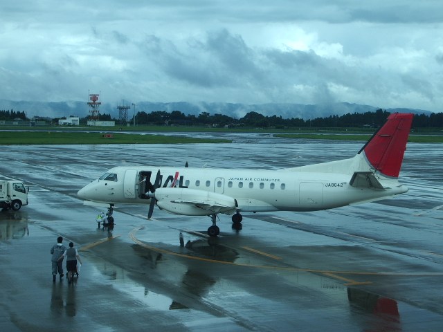 雨で水がたまった鹿児島空港の滑走路とプロペラ機