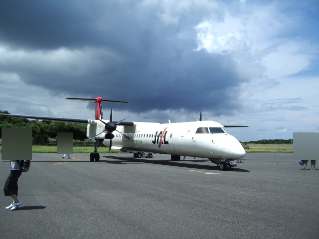 屋久島空港に駐機したプロペラ機と、どんよりした空