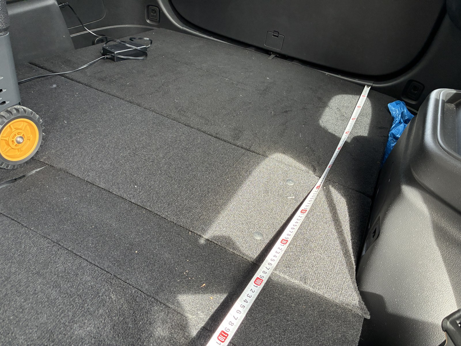 バックドアから前席までメジャーを伸ばして車中泊スペースの長さを測っているところ。195cmを少し超える